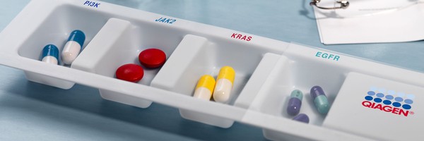 Tablettenschale mit verschiedenen Pillen, beschriftet mit PIK3, JAK2, KRAS, EGFR und Qiagen-Logo.