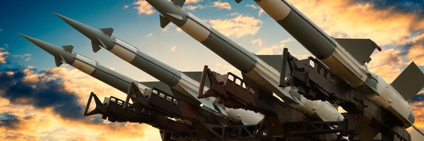 Mehrere Raketen auf einem Abschussgerät vor einem dramatischen Himmel bei Sonnenuntergang.