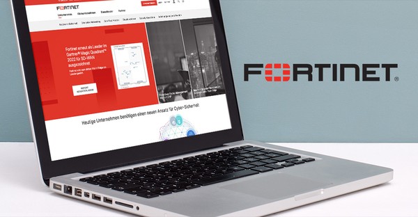 Laptop mit geöffneter Fortinet-Website, daneben das Fortinet-Logo auf einer blauen Wand.