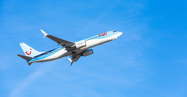 Flugzeug im Steigflug vor blauem Himmel.