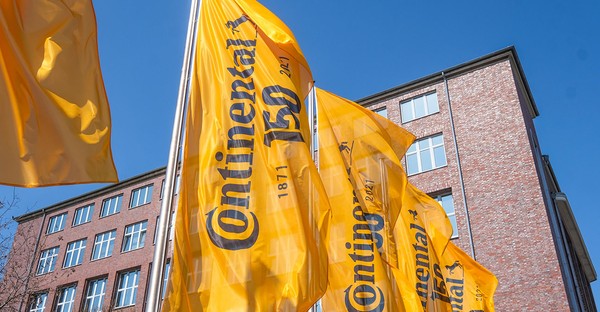 Gelbe Continental-Flaggen wehen vor einem Backsteingebäude unter blauem Himmel.