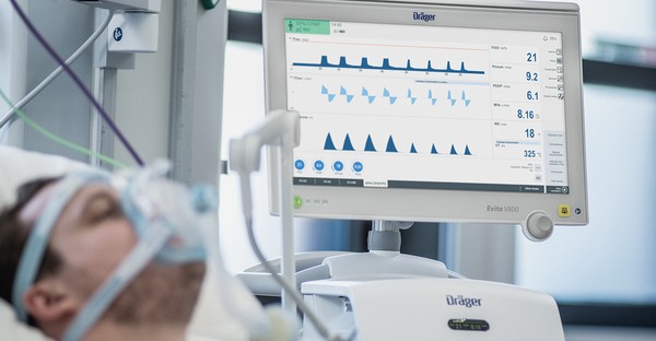 Patient mit Beatmungsgerät und Monitor mit Vitaldaten im Krankenhaus.