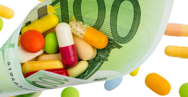 Verschiedene bunte Pillen in einem gerollten 100-Euro-Schein.