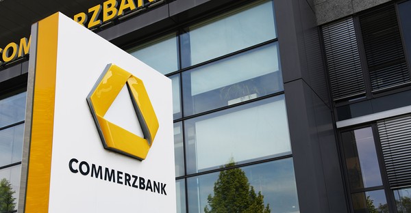 Gebäude mit Commerzbank-Logo auf einem Schild, moderne Glasfassade im Hintergrund.