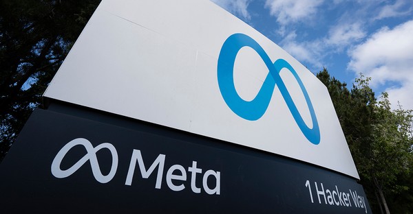 Meta-Logo auf einem Schild mit der Adresse 1 Hacker Way, umgeben von Bäumen und blauem Himmel.