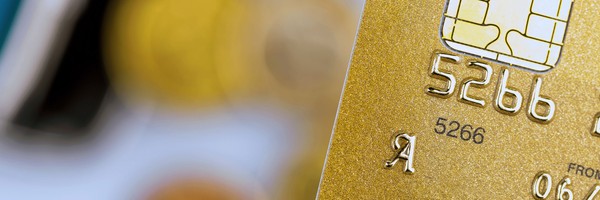 Nahaufnahme einer goldenen Kreditkarte mit Chip und teilweise sichtbaren Zahlen.