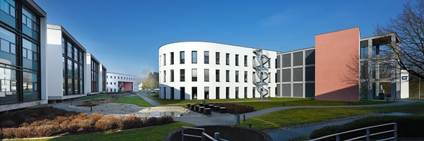 Moderne Bürogebäude mit Glasfassaden und einem runden, weißen Gebäude bei klarem Himmel.