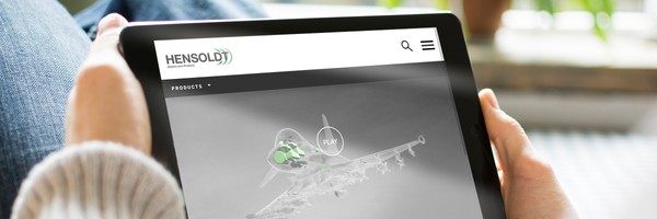 Person hält ein Tablet mit der Hensoldt-Website, die ein Flugzeugmodell zeigt.